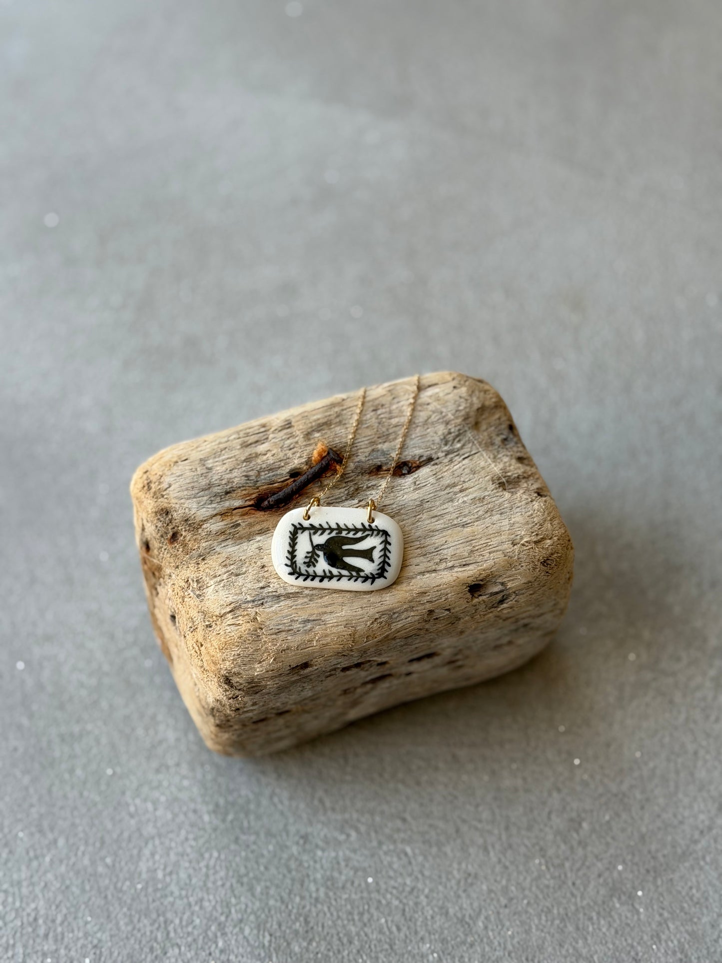 Pieza de porcelana con golondrina y cadena de acero inoxidable.