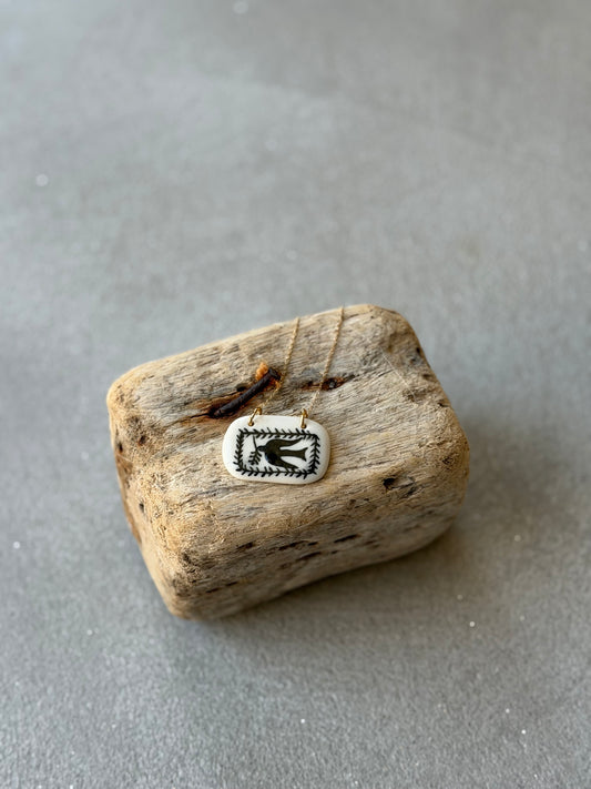 Pieza de porcelana con golondrina y cadena de acero inoxidable.
